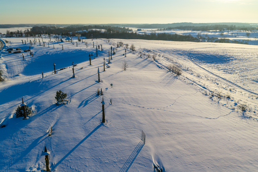 Aerial view of the Hill of Angels featuring tall wooden sculptures scattered across a snow covered landscape under a clear winter sky in Traku rajonas Vilniaus apskritis Lithuania. Aerial view of the Hill of Angels featuring tall wooden sculptures scattered across a snow covered landscape under a clear winter sky in Traku rajonas Vilniaus apskritis Lithuania.