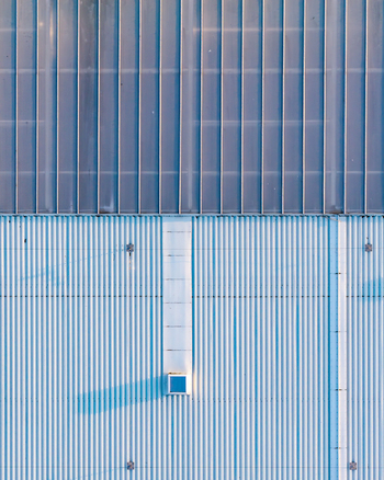 Aerial view of a corrugated metal roof with a central skylight and clean geometric lines on an industrial building in Plock Mazowieckie Poland.