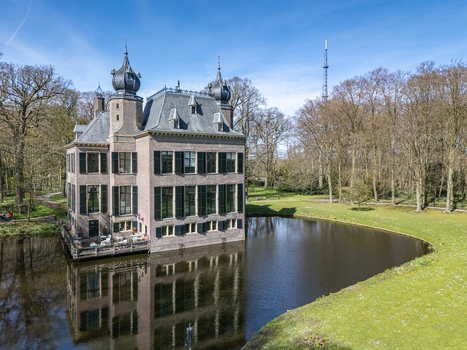 Aerial view of the historic Landgoed Oud Poelgeest castle its reflection shimmering in the surrounding moat standing proud against the clear sky Oegstgeest Zuid Holland Netherlands. Aerial view of the historic Landgoed Oud Poelgeest castle its reflection shimmering in the surrounding moat standing proud against the clear sky Oegstgeest Zuid Holland Netherlands.