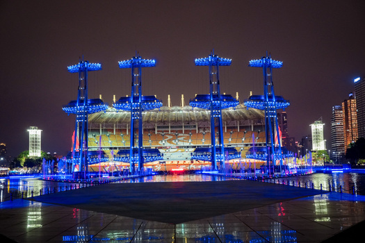 Guangzhou China 24 February 2024 View of the Tianhe Sports Center illuminated at night with blue light towers and a reflecting pool in the foreground. Guangzhou China 24 February 2024 View of the Tianhe Sports Center illuminated at night with blue light towers and a reflecting pool in the foreground.