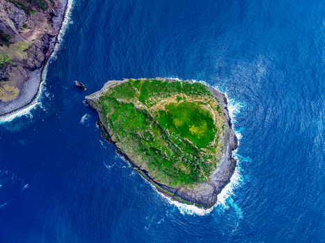 Aerial view of a lush green islet surrounded by the deep blue Atlantic waters a rugged coastline meeting the sea s embrace Flores A&ccedil;ores Portugal.