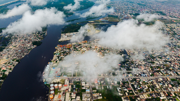 Aerial view of Satellite Town with industrial storage tanks dense urban housing and a river winding through the landscape in Lagos Lagos Nigeria.