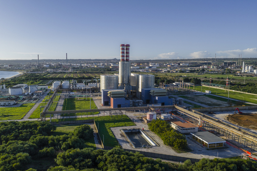 Aerial view of industrial architecture contrasting with lush greenery towering structures against a clear sky SP114 Erg Petroli Spa Syracuse Sicilia Italy.