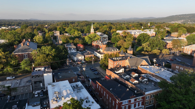 Aerial view of the historic cityscape featuring brick buildings lush green trees and urban streets under a clear sky in Charlottesville Virginia United States.