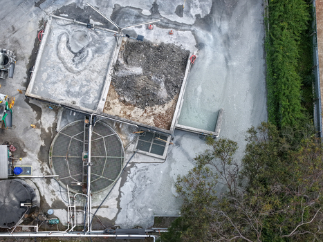 Melbourne Australia 25 September 2026 Aerial view of an industrial facility with a large circular tank concrete basins gravel areas pipes and surrounding trees.