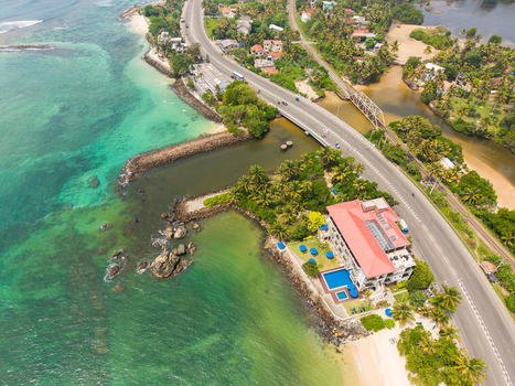 Aerial view of Devil s Rock and the scenic coastline with a winding road and lush tropical vegetation in Ahangama Southern Province Sri Lanka. Aerial view of Devil s Rock and the scenic coastline with a winding road and lush tropical vegetation in Ahangama Southern Province Sri Lanka.