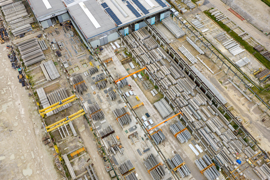 Aerial view of a factory yard featuring rows of prestressed concrete elements industrial buildings and overhead cranes in Poland.