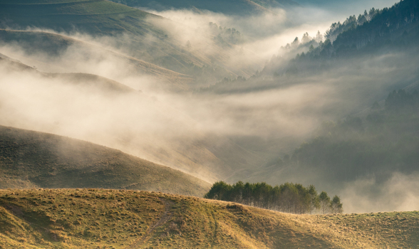 View of the misty rolling hills and forest patches in the rural landscape of Pestera Brasov Romania. View of the misty rolling hills and forest patches in the rural landscape of Pestera Brasov Romania.