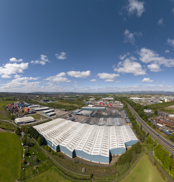 04 May 2026 Aerial view of a large industrial complex with white corrugated roofs bordered by green fields and a busy highway under a bright blue sky with clouds. 04 May 2026 Aerial view of a large industrial complex with white corrugated roofs bordered by green fields and a busy highway under a bright blue sky with clouds.