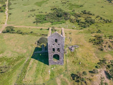 Aerial view of the historic stone mine engine house at Phoenix United Mine surrounded by grassy fields and rolling hills in Minions Cornwall United Kingdom. Aerial view of the historic stone mine engine house at Phoenix United Mine surrounded by grassy fields and rolling hills in Minions Cornwall United Kingdom.