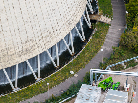 Aerial view of the cooling tower at Heizkraftwerk Reuter West with water cascading down the base surrounded by industrial infrastructure and green spaces in Berlin Berlin Germany.
