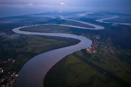 Aerial view of a winding river flowing through dense mangrove forests and lush vegetation with small settlements along the banks in Opobo Town Rivers Nigeria. Aerial view of a winding river flowing through dense mangrove forests and lush vegetation with small settlements along the banks in Opobo Town Rivers Nigeria.