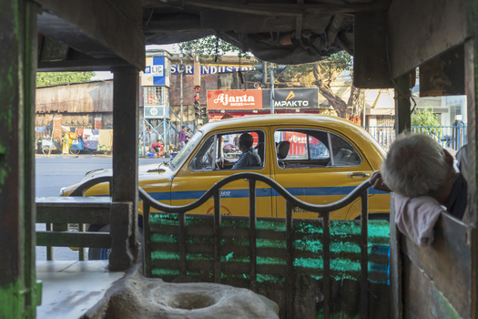 Kolkata India 05 December 2024 View of a classic yellow taxi cruising past the bustling streets of Kolkata framed by the weathered interior of another vehicle. Kolkata India 05 December 2024 View of a classic yellow taxi cruising past the bustling streets of Kolkata framed by the weathered interior of another vehicle.