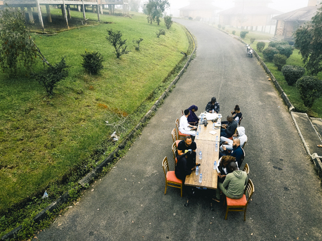 Aerial view of people gathered around a long table on a road near a lush green hillside the scene shrouded in mist Obudu Cross River Nigeria.
