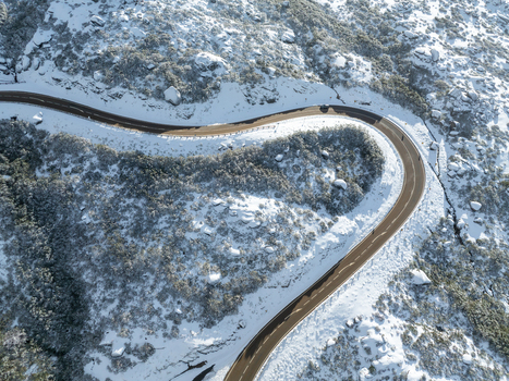 Aerial view of a road winding through the snowy mountainous terrain of Serra da Estrela contrasting with the dark evergreens São Romão Guarda District Portugal. Aerial view of a road winding through the snowy mountainous terrain of Serra da Estrela contrasting with the dark evergreens São Romão Guarda District Portugal.