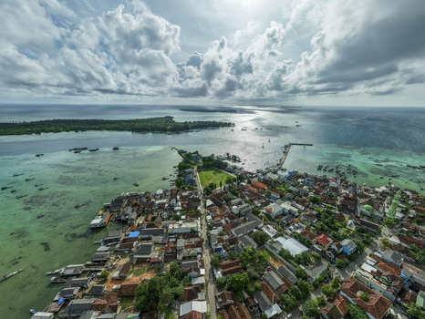 Aerial view of the town extending into the turquoise sea the vibrant greens of the island contrasting with the white clouds Karimunjawa Central Java Indonesia. Aerial view of the town extending into the turquoise sea the vibrant greens of the island contrasting with the white clouds Karimunjawa Central Java Indonesia.