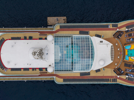 Aerial view of a cruise ship deck with a glass covered pool sun loungers and walking paths surrounded by deep blue sea in Cannes Provence Alpes Cote d Azur France. Aerial view of a cruise ship deck with a glass covered pool sun loungers and walking paths surrounded by deep blue sea in Cannes Provence Alpes Cote d Azur France.