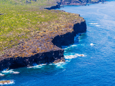 Aerial view of dramatic cliffs adorned with vibrant green vegetation plunging into the azure ocean at Miradouro Prainha Pico Azores Portugal. Aerial view of dramatic cliffs adorned with vibrant green vegetation plunging into the azure ocean at Miradouro Prainha Pico Azores Portugal.