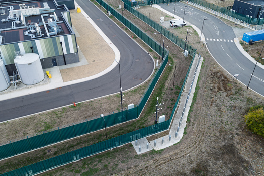 Aerial view of a modern data center facility with industrial buildings large storage tanks paved roads and security fencing in the United Kingdom. Aerial view of a modern data center facility with industrial buildings large storage tanks paved roads and security fencing in the United Kingdom.