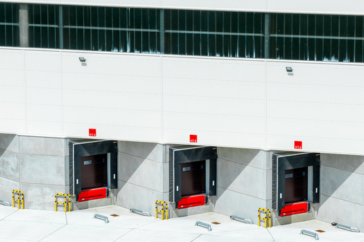 Aerial view of loading docks with red levelers and yellow safety bollards at a modern warehouse facility in Poland.
