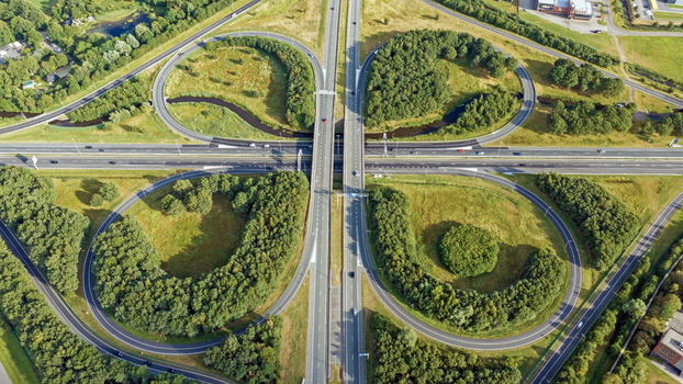 Aerial view of the cloverleaf Drachten interchange featuring multi level highway roads lush green spaces and surrounding trees in Drachten Friesland Netherlands. Aerial view of the cloverleaf Drachten interchange featuring multi level highway roads lush green spaces and surrounding trees in Drachten Friesland Netherlands.