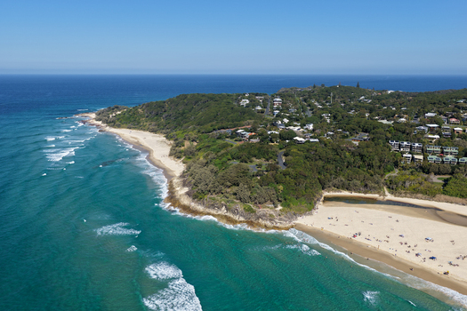 Aerial view of North Stradbroke Island coastline with sandy beaches turquoise ocean waves lush green vegetation and coastal houses in Redland City Queensland Australia. Aerial view of North Stradbroke Island coastline with sandy beaches turquoise ocean waves lush green vegetation and coastal houses in Redland City Queensland Australia.