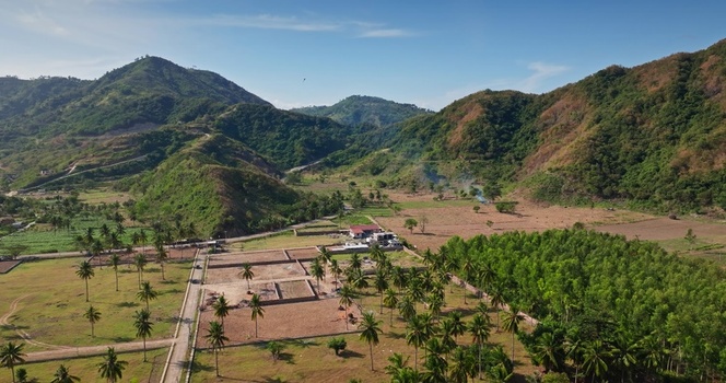 Aerial view of lush green hills palm trees and agricultural fields in the rural landscape of Lombok West Nusa Tenggara Indonesia.