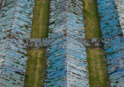 Aerial view of abandoned greenhouses with broken blue glass panels and rows of green grass in Vilnius County Lithuania. Aerial view of abandoned greenhouses with broken blue glass panels and rows of green grass in Vilnius County Lithuania.