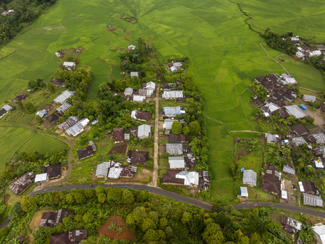 Aerial view of the unique Lingko Spider Web Rice Fields surrounded by lush green landscapes traditional village houses and winding roads in Ruteng East Nusa Tenggara Indonesia.
