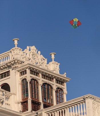 View of a colorful kite flying in the clear blue sky above the ornate historic architecture of a building in Lahore Punjab Pakistan.