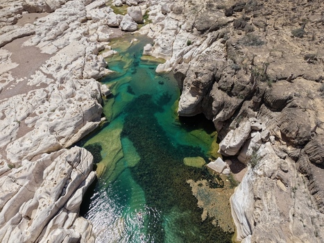 Aerial view of turquoise waters wind through the rugged sun drenched rocks of Kalysan Canyon a stark contrast of textures and tones Kalysan canyon Socotra Yemen.