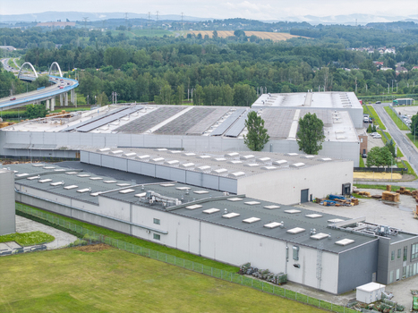 Aerial view of a large logistics hub with industrial warehouses flat roofs with skylights green fields and a nearby highway bridge in Skawina Lesser Poland Voivode Poland. Aerial view of a large logistics hub with industrial warehouses flat roofs with skylights green fields and a nearby highway bridge in Skawina Lesser Poland Voivode Poland.