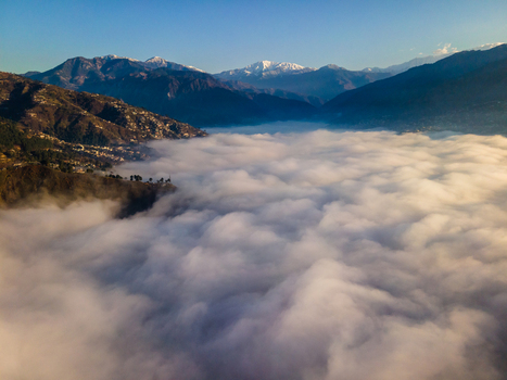 Aerial view of Muzaffarabad valley covered in a thick sea of clouds with snow capped peaks in the distance under a clear blue sky Muzaffarabad Azad Kashmir Pakistan. Aerial view of Muzaffarabad valley covered in a thick sea of clouds with snow capped peaks in the distance under a clear blue sky Muzaffarabad Azad Kashmir Pakistan.