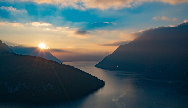 Aerial view of the Swiss Alps at sunset with golden light reflecting over the calm lake and surrounding mountains in Airolo Ticino Switzerland. Aerial view of the Swiss Alps at sunset with golden light reflecting over the calm lake and surrounding mountains in Airolo Ticino Switzerland.