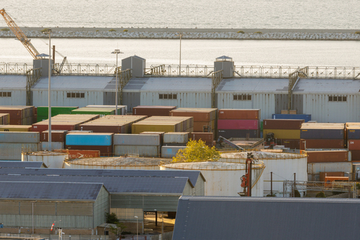 Aerial view of Ancona Port featuring rows of colorful shipping containers large industrial storage tanks and warehouse facilities under warm golden hour light in Ancona Marche Italy. Aerial view of Ancona Port featuring rows of colorful shipping containers large industrial storage tanks and warehouse facilities under warm golden hour light in Ancona Marche Italy.