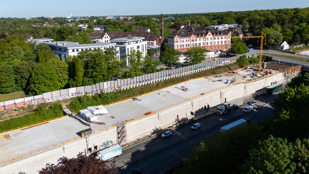 Aerial view of the A7 motorway tunnel construction site in Bahrenfeld with trucks on the road and lush green trees Hamburg Hamburg Germany.