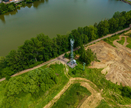 Aerial view of a telecommunications tower situated near a lake surrounded by lush trees and dirt paths in Zebrak Central Bohemian Region Czechia. Aerial view of a telecommunications tower situated near a lake surrounded by lush trees and dirt paths in Zebrak Central Bohemian Region Czechia.