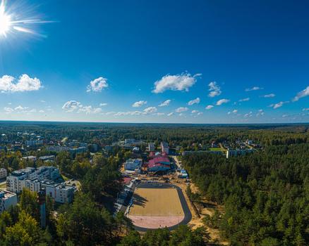 Aerial view of a residential area and sports field surrounded by dense pine forests in Latvia. Aerial view of a residential area and sports field surrounded by dense pine forests in Latvia.