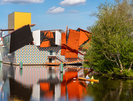 Groningen Netherlands 23 April 2024 View of the Groninger Museum featuring colorful modern architecture and a yellow tower reflected in the canal with people in a rowing boat. Groningen Netherlands 23 April 2024 View of the Groninger Museum featuring colorful modern architecture and a yellow tower reflected in the canal with people in a rowing boat.