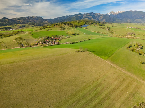 Aerial view of rolling green hills and agricultural fields with the Tatra mountains in the background near Liptovsky Trnovec Zilina Region Slovakia.