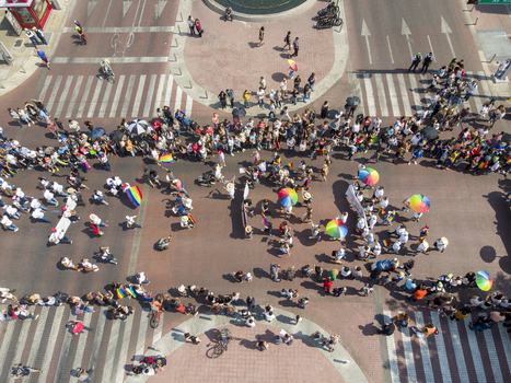 Guadalajara Mexico 01 June 2019 Aerial view of the LGBT pride parade with crowds of people walking through the intersection carrying rainbow umbrellas and flags.