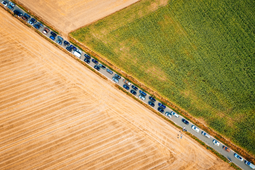 Aerial view of a long line of cars parked on a narrow road between harvested and green agricultural fields during the Open Beatz Festival in Herzogenaurach Bayern Germany. Aerial view of a long line of cars parked on a narrow road between harvested and green agricultural fields during the Open Beatz Festival in Herzogenaurach Bayern Germany.
