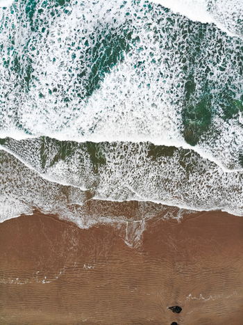 Aerial view of waves crashing onto the sandy beach at Downhill Beach in Coleraine Northern Ireland United Kingdom. Aerial view of waves crashing onto the sandy beach at Downhill Beach in Coleraine Northern Ireland United Kingdom.