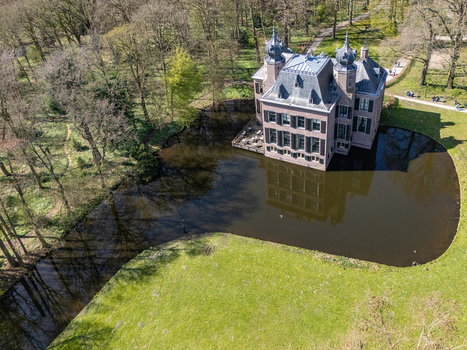 Aerial view of a medieval castle reflecting on the still moat waters surrounded by the vibrant greens and browns of the forest Oegstgeest Zuid Holland Netherlands. Aerial view of a medieval castle reflecting on the still moat waters surrounded by the vibrant greens and browns of the forest Oegstgeest Zuid Holland Netherlands.