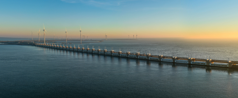 Aerial view of the Delta Projects Netherlands storm surge barrier and offshore wind turbines at sunset in Vrouwenpolder Zeeland Netherlands.