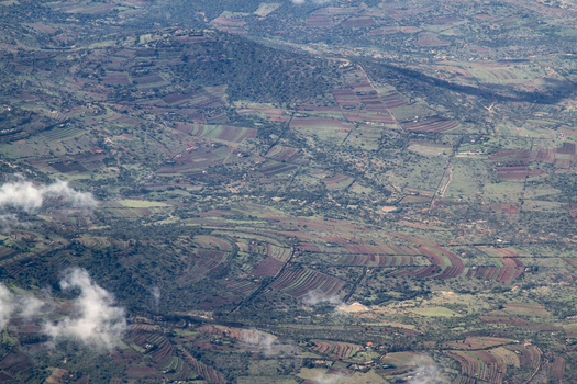 View of the hilly landscape with terraced agricultural fields and scattered trees under light clouds in Tiwi Wilaya ya Kwale Kenya. View of the hilly landscape with terraced agricultural fields and scattered trees under light clouds in Tiwi Wilaya ya Kwale Kenya.