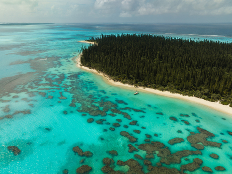 Aerial view of lush green island fringed by a white sandy beach and turquoise waters Pine Island New Caledonia. Aerial view of lush green island fringed by a white sandy beach and turquoise waters Pine Island New Caledonia.