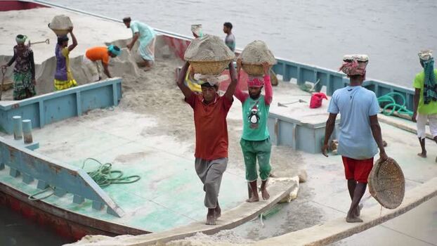 View of laborers carrying sand on a barge in Aminbazar Bangladesh.