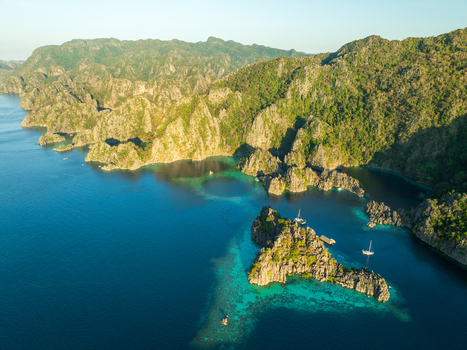 Aerial view of Twin Lagoon surrounded by dramatic limestone cliffs and turquoise waters with boats anchored in the bay in Coron Mimaropa Philippines. Aerial view of Twin Lagoon surrounded by dramatic limestone cliffs and turquoise waters with boats anchored in the bay in Coron Mimaropa Philippines.