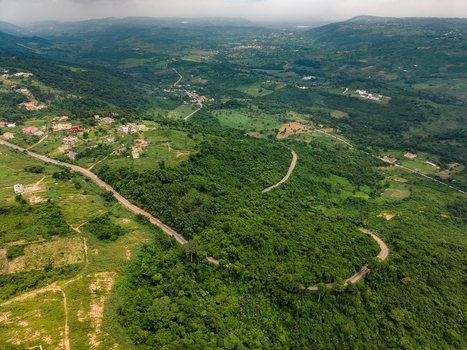 Aerial view of a winding road cutting through lush green hills and dense tropical vegetation in Ghana. Aerial view of a winding road cutting through lush green hills and dense tropical vegetation in Ghana.